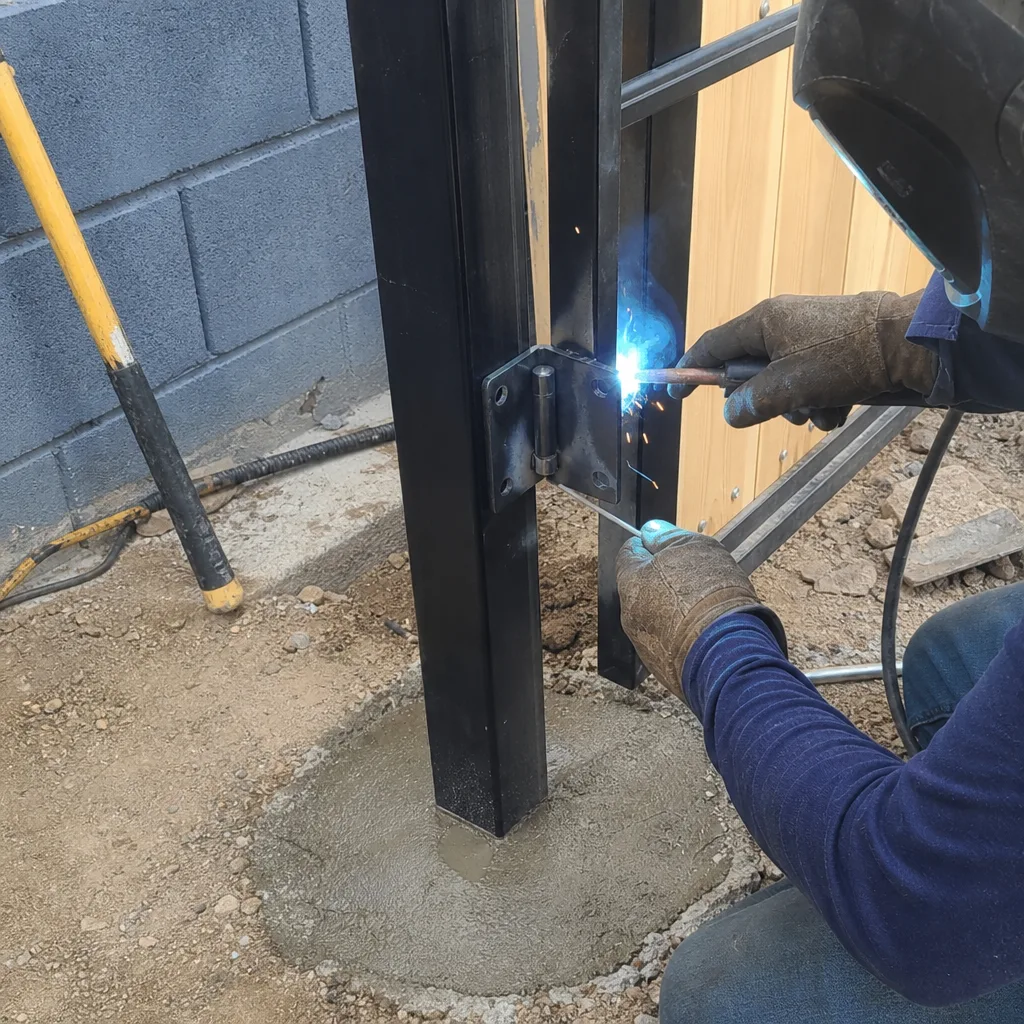 Professional welder performing gate installation with arc welding tool